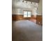 Spacious carpeted living room with wood-paneled walls, a large window, and ceiling fan at 2195 Wilson Rd, Conyers, GA 30012