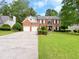 Charming two-story red brick home featuring a two-car garage, manicured lawn and mature landscaping at 2049 Mclain Nw Rd, Acworth, GA 30101