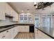 Clean kitchen with black countertops, an undermount sink, white cabinets, and gray wood-look floors at 2049 Mclain Nw Rd, Acworth, GA 30101