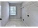 Neutral laundry room featuring tile floor, window and wire shelving for storage at 2049 Mclain Nw Rd, Acworth, GA 30101
