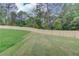 Landscaped backyard featuring a wood fence, green grass, and mature trees, providing privacy and a serene atmosphere at 3203 Bold Springs Rd, Dacula, GA 30011