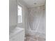 A new bathroom with a window and tiled shower/bathtub, currently wrapped in protective plastic, ready for finishing touches at 3203 Bold Springs Rd, Dacula, GA 30011