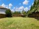 Spacious backyard featuring a well-maintained lawn, wooden fence, and mature trees for privacy at 6215 Barley Sq, Sugar Hill, GA 30518