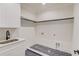 Laundry room featuring white cabinets, a sink, herringbone tile flooring, and black hardware at 3205 Bold Springs Rd, Dacula, GA 30019