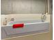 Enclosed bathtub with tile surround features mounted chrome faucet and red towel at 925 Champions Way, Mcdonough, GA 30252