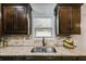 Close-up of the kitchen sink area with granite countertops, tiled backsplash, and dark wood cabinetry, adding elegance at 127 Grayson Myers Dr, Villa Rica, GA 30180