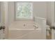 Relaxing main bathroom featuring a soaking tub and a window letting in natural light at 3717 Lockerbie Ln, Powder Springs, GA 30127