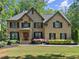 Charming two-story brick home with a well-manicured lawn, mature trees, and a welcoming red front door at 4680 Brighton Lake Dr, Cumming, GA 30040