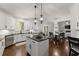 Stylish kitchen featuring white cabinets, a center island, black countertops, and modern pendant lighting at 4680 Brighton Lake Dr, Cumming, GA 30040