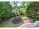 Landscaped backyard with mulched area, a young tree, mature trees, and grassy area at 5260 Harbury Ln, Suwanee, GA 30024
