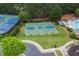 Aerial view of a community basketball court surrounded by well-manicured lawns and trees adjacent to a tennis court at 5260 Harbury Ln, Suwanee, GA 30024