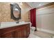 Bathroom features a dark wood vanity, decorative wallpaper, and a walk-in shower with red shower curtain at 5260 Harbury Ln, Suwanee, GA 30024