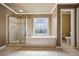 Bright bathroom featuring a soaking tub, decorative window, and a tiled stand-up shower at 5260 Harbury Ln, Suwanee, GA 30024