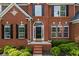 Close-up of the front door and facade of the brick home, highlighting the landscaping at 5260 Harbury Ln, Suwanee, GA 30024