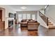 Open-concept living room with fireplace, built-in shelving, hardwood floors, and staircase to upper level at 5870 Shiloh Woods Dr, Cumming, GA 30040