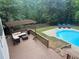 Deck view of a stunning outdoor pool with a pergola-covered seating area and plenty of space for relaxation at 1020 Travitine Trl, Loganville, GA 30052