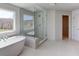 Bright bathroom featuring a freestanding tub and glass-enclosed shower next to a window with a view at 3066 Reserve Ct Sw, Conyers, GA 30094