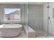 Spa bathroom featuring a freestanding tub, glass-enclosed shower with river rock floor, and a view from the window at 3066 Reserve Ct Sw, Conyers, GA 30094