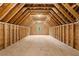 Unfinished attic space showcasing exposed wooden beams, framing, and natural light from a window at 131 Forsyth Park Ln, Woodstock, GA 30188