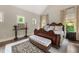 A bedroom featuring a large bed, rug, bench and windows overlooking the surrounding greenery at 131 Forsyth Park Ln, Woodstock, GA 30188