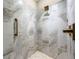 Shower with white and gray marble tiling, pebble floor, and bronze fixtures at 131 Forsyth Park Ln, Woodstock, GA 30188