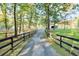 Picturesque driveway to the estate, bordered by a black fence, green lawns, and verdant trees, exuding tranquility at 2203 Arbor Hill Rd, Canton, GA 30115