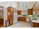 Bright kitchen featuring wood cabinets, white appliances, and a large window at 2203 Arbor Hill Rd, Canton, GA 30115