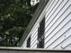 Exterior side shot shows white siding and windows with security bars, protected by greenery at 244 Hilltop Sw Dr, Atlanta, GA 30315