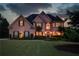 Elegant brick home featuring manicured lawn, lush landscaping and warm, inviting exterior lighting at 1608 Mulberry Lake Dr, Dacula, GA 30019