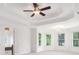 Bedroom featuring tray ceiling, ceiling fan, neutral carpet, and several windows at 315 Hembree Grove Trce, Roswell, GA 30076