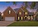 Attractive brick home with a well-maintained lawn, garage, and inviting entrance at dusk at 315 Hembree Grove Trce, Roswell, GA 30076