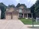 Charming two-story home with a manicured lawn, attached two-car garage, and a welcoming front porch at 6725 Grove Meadows Ln, Cumming, GA 30028