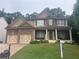 Charming two-story home with stone accents, covered front porch, and a manicured lawn at 6725 Grove Meadows Ln, Cumming, GA 30028