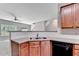 Kitchen featuring wood cabinets, sleek black appliances, and a view of the dining area at 2173 Pebble Beach Dr, Lawrenceville, GA 30043