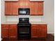 A kitchen featuring wooden cabinets, a black range, black microwave, and light countertops at 2173 Pebble Beach Dr, Lawrenceville, GA 30043