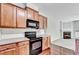Kitchen featuring wooden cabinets, sleek black appliances, and a view of the cozy living area at 2173 Pebble Beach Dr, Lawrenceville, GA 30043