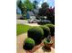 Landscaped front yard with manicured bushes and glimpses of neighboring homes on a sunny day at 215 Boca Ciega Ct, Alpharetta, GA 30022