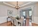 Cozy dining room featuring hardwood floors, an elegant chandelier, and wainscoting at 4885 Maristone Landing Way, Cumming, GA 30040