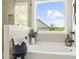 Well lit bathroom featuring a soaking tub next to a large window overlooking the green landscaping at 2749 Porches Ln, Dacula, GA 30019