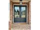Elegant front door with glass panels, brick surround, and overhead light fixture at 4010 Sierra Knolls Ct, Cumming, GA 30040