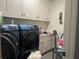 Laundry room with two blue Samsung washing machines and white cabinets at 312 Archway Ln, Peachtree City, GA 30269