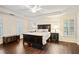 Spacious primary bedroom with a tray ceiling, dark furniture, and windows with shutters at 946 Cornwall Sw Ct, Marietta, GA 30064