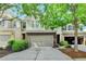 Charming townhome featuring a two-car garage, brick accents, and lush green landscaping at 3123 Cross Creek Dr, Cumming, GA 30040