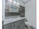 Stylish bathroom featuring gray cabinets, a granite countertop, decorative mirror, and a gray wood-look accent wall at 1265 Watercrest Cir, Lawrenceville, GA 30043