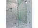 Beautiful glass-enclosed shower with marble tile, a rain shower head, and built in shelf at 1265 Watercrest Cir, Lawrenceville, GA 30043