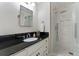 Modern bathroom features marble-look tiling in glass-enclosed shower, black granite countertop, and white cabinets at 330 Broad Leaf Ct, Johns Creek, GA 30022
