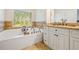 Well lit bath with a large window overlooking the outdoors next to a soaking tub at 286 Blue Pointe Ct, Suwanee, GA 30024