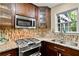 Chef's kitchen with stainless steel appliances, dark cabinets, granite counters, and designer tile backsplash at 4311 Sentinel Nw Pl, Kennesaw, GA 30144