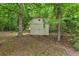 Exterior view of backyard shed surrounded by trees and natural landscaping providing extra storage at 7370 N Mitchell Ct, Villa Rica, GA 30180