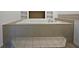 Close-up view of a jacuzzi tub in the primary bath with tile platform and stairs at 4335 Northwind Dr, Ellenwood, GA 30294